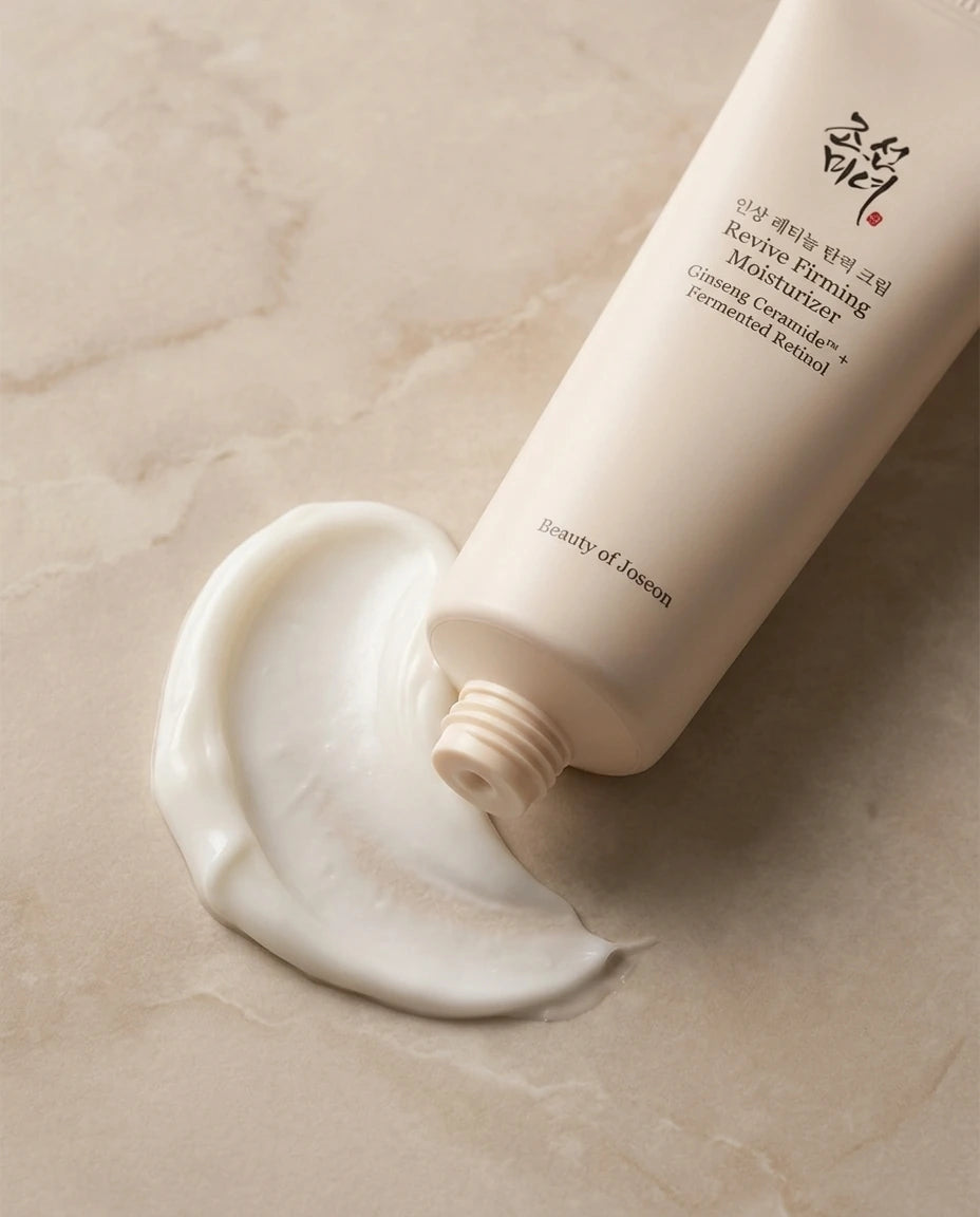 L'Angle : Gros plan macro de biais, à hauteur d'œil.  Le Fond : Le tube est posé à plat sur une surface en marbre mat beige. Juste à côté du bouchon, une magnifique ondulation (swatch) de crème blanche, onctueuse et veloutée est visible, montrant sa texture riche.  Le Prompt :  Macro commercial beauty shot of the Beauty of Joseon moisturizer tube lying flat on a smooth beige matte marble surface. Next to the opening cap, there is an elegant, thick, and velvety swirl swatch of the white face cream, showing i