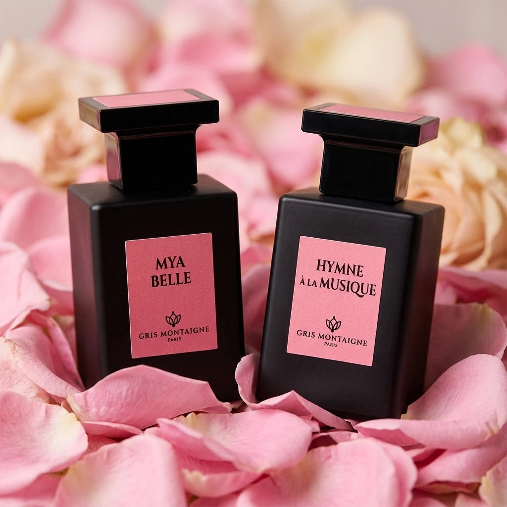 Éclat floral : Un gros plan sur les deux flacons de parfum "Mya Belle" et "Hymne à la Musique" posés sur un lit de pétales de roses roses. La lumière est douce et diffuse, mettant en valeur les couleurs délicates des flacons. (gemini-3.1-flash-image-preview)