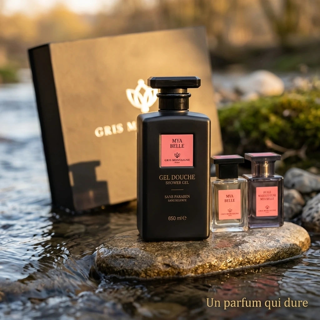 Un parfum qui dure : Un gros plan sur un flacon de parfum Gris Montaigne posé sur une pierre plate au bord d'un ruisseau. L'eau coule doucement autour de la pierre. La lumière du soleil couchant crée une atmosphère paisible." (gemini-3.1-flash-image-preview)