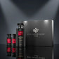A sleek, minimalist advertising product shot featuring the luxury black closed gift box of "Gris Montaigne Paris" with its iconic silver floral logo shining brightly. Placed directly in front of the box, slightly to the side, is the "Rose Indomptable" black perfume bottle, creating a clean reflection on a glossy black mirror floor. The background is a clean, abstract gradient of dark gray and deep charcoal. Graphic studio lighting with sharp spotlights creates a dramatic halo effect on the packaging. Elegan