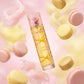 Une scène fantaisiste avec la bouteille "Pink Sugar Creamy Sunshine" (image_2.png) suspendue et flottant parmi des formes pastel de macaron doux et des volutes de sucre filé dans une palette rose clair et jaune. (gemini-3-pro-image-preview)
