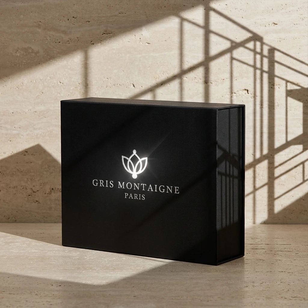 Un plan moyen à 45 degrés du coffret fermé de image_20c739.jpg disposé sur un sol en travertin beige clair au fini mat. Un projecteur de studio projette l'ombre graphique, nette et texturée de lignes architecturales modernes directement sur le mur arrière et sur le flanc du coffret. Le logo argenté de image_20c739.jpg capte une lumière rasante ultra-réaliste. Style : Studio packshot contemporain. (gemini-3-pro-image-preview)