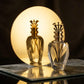 Un plan moyen du flacon sculptural de image_2e6d8a.jpg debout sur une dalle de miroir vieilli aux reflets argentés sablés. Derrière le produit, un disque de plexiglas doré translucide rétroéclairé recrée une pleine lune artificielle parfaite. La silhouette en or de la couronne impériale de image_2e6d8a.jpg se détache magnifiquement en ombre chinoise inversée, révélant ses lignes métalliques tranchantes. Style : Éditorial de mode haut de gamme. (gemini-3-pro-image-preview)