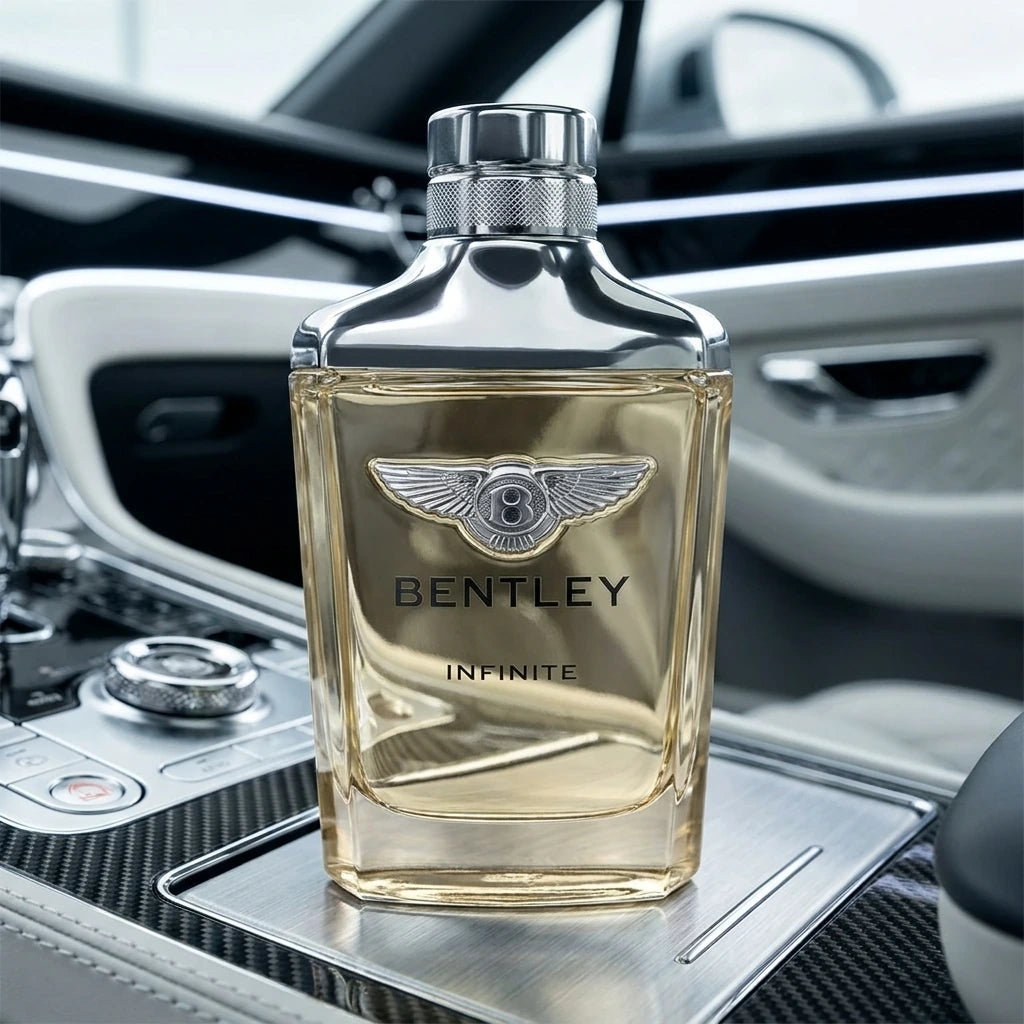 Une photographie publicitaire au format carré 1200x1200px. Le flacon de parfum "Bentley Infinite" de image_8532e2.jpg est photographié de face, parfaitement centré et d'une netteté absolue. Il repose sur la console centrale en fibre de carbone et aluminium brossé d'un coupé de sport moderne. L'arrière-plan présente l'intérieur minimaliste et technologique du véhicule avec des éclairages LED linéaires blancs et froids. La lumière du jour se reflète proprement sur les épaules chromées et met en relief l'emblè