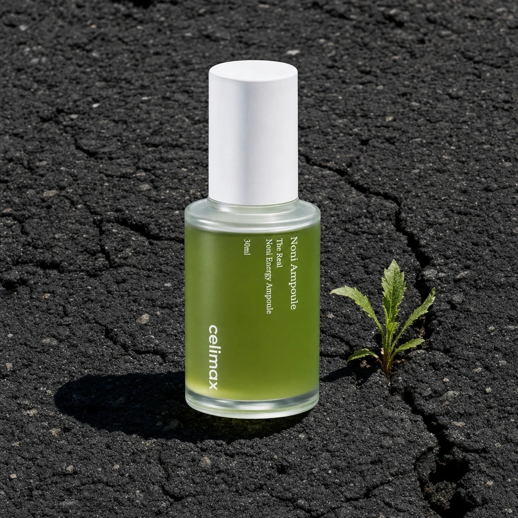 Commercial product shot, stark contrast style. The elegant 30ml glass bottle of Celimax Noni Energy Ampoule sits directly on rough, dark, deeply cracked asphalt pavement. The texture of the dry, damaged tar is highly detailed. A single, small green weed grows out of a nearby crack. Harsh midday sun creates strong, defined shadows, emphasizing the textures. The product remains clean and pristine against the urban decay. No special effects, raw realism. Shot on 70mm lens, F7 aperture, ISO 250. 8k resolution. 